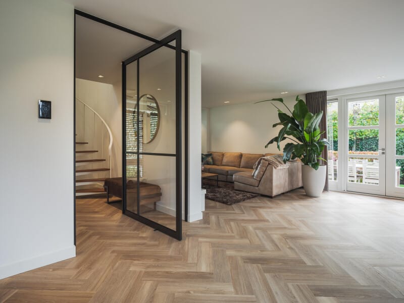 Warme visgraat PVC vloer in een woonkamer met een glazen deur en veel daglicht